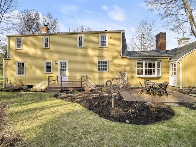 back of house featuring a wooden deck, a patio, a chimney, and a yard