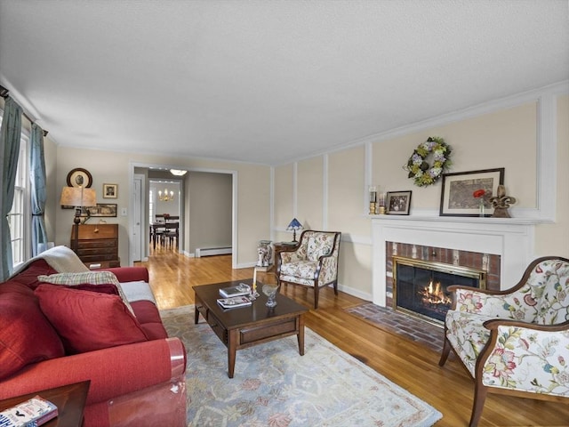 living room with a fireplace, crown molding, baseboard heating, and wood finished floors