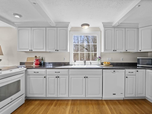 kitchen featuring a sink, a textured ceiling, white appliances, and beam ceiling