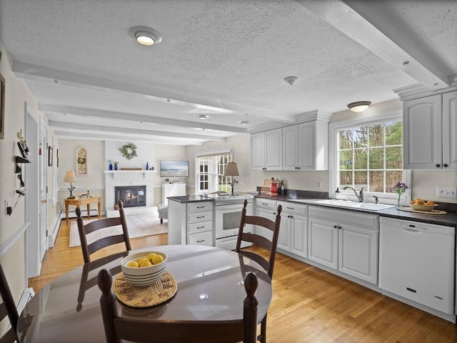 kitchen with a sink, a textured ceiling, a peninsula, and white appliances