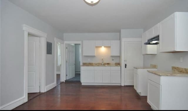 kitchen with light countertops, white cabinets, dark wood-style flooring, and under cabinet range hood