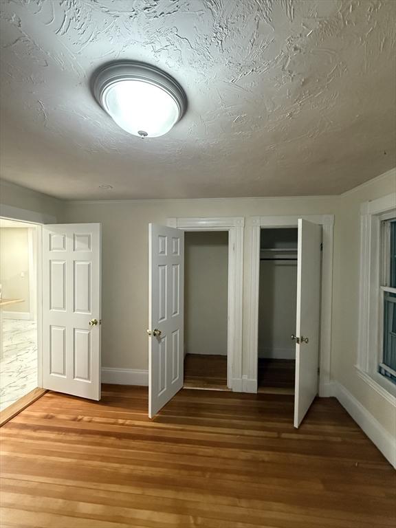 9-11 Elson Rd, Waltham, MA 02451 - unfurnished bedroom with light wood finished floors, a closet, and a textured ceiling