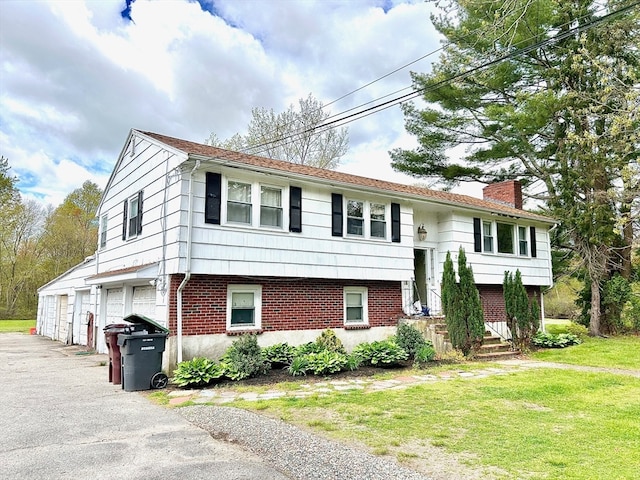 split foyer home featuring a front lawn and a garage