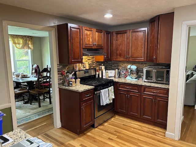 kitchen featuring light stone countertops, stainless steel appliances, light hardwood / wood-style floors, and backsplash