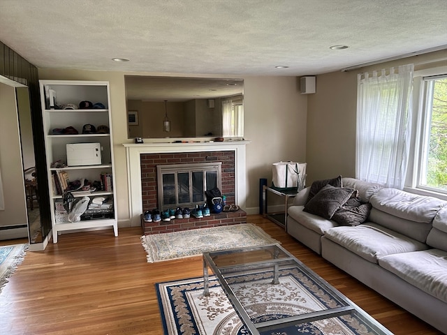 living room featuring a textured ceiling, a healthy amount of sunlight, a fireplace, and wood-type flooring