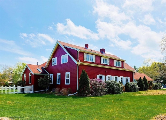 view of front of home with fence, a chimney, and a front yard