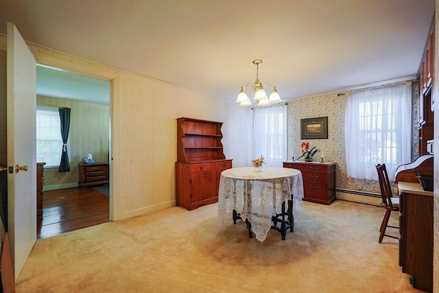 dining space featuring a baseboard heating unit, light colored carpet, a notable chandelier, and a wealth of natural light
