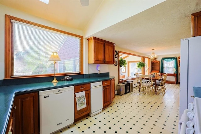 kitchen with dark countertops, dishwasher, range, light floors, and vaulted ceiling