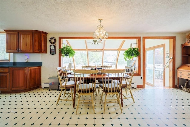 dining room with an inviting chandelier, a baseboard radiator, a textured ceiling, and a wealth of natural light