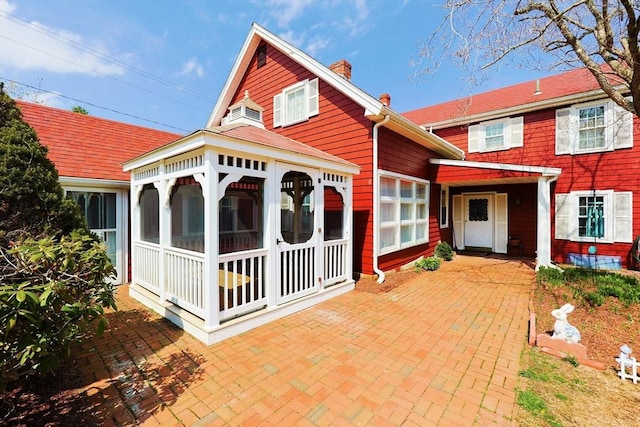 view of front facade featuring a sunroom, a chimney, and a gazebo