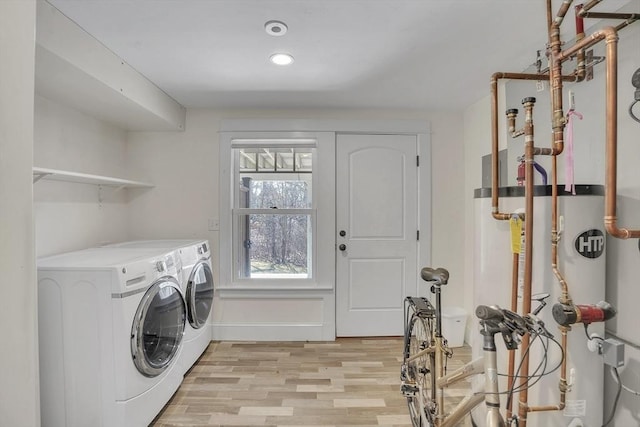 clothes washing area featuring laundry area, washing machine and clothes dryer, light wood-type flooring, water heater, and recessed lighting