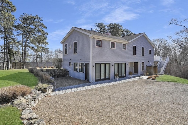 view of front of property featuring gravel driveway, a chimney, stairway, and fence