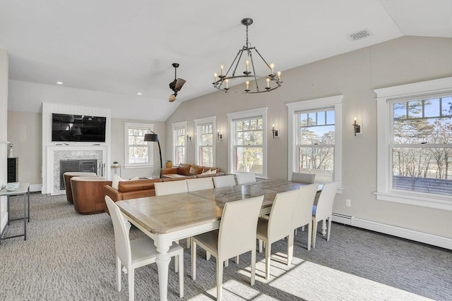 dining area featuring vaulted ceiling, visible vents, a fireplace, and a healthy amount of sunlight