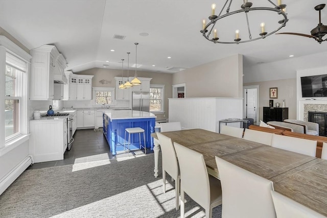 dining room with visible vents, a glass covered fireplace, lofted ceiling, baseboard heating, and recessed lighting