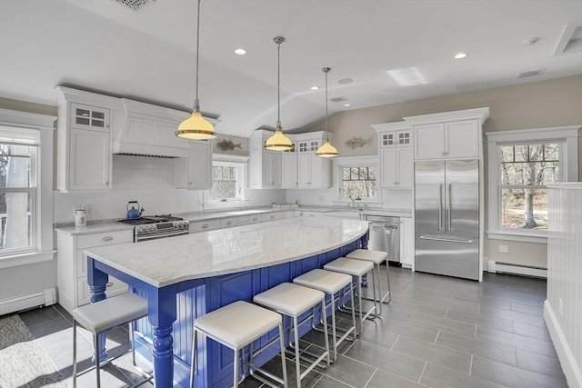 kitchen with stainless steel appliances, a baseboard radiator, backsplash, white cabinets, and a kitchen island