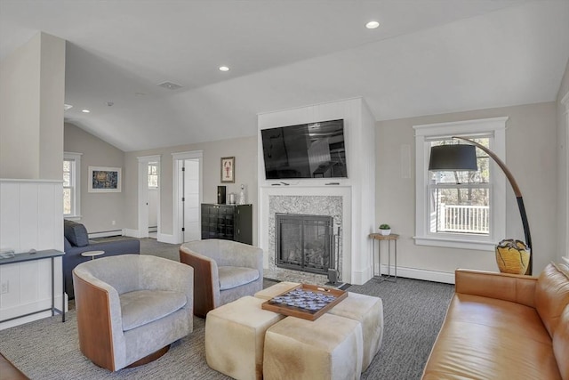 living room featuring plenty of natural light, visible vents, vaulted ceiling, and a glass covered fireplace