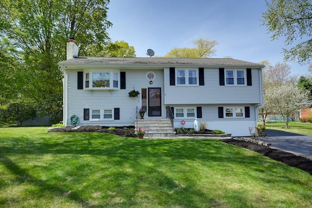 split foyer home with entry steps, a chimney, and a front lawn