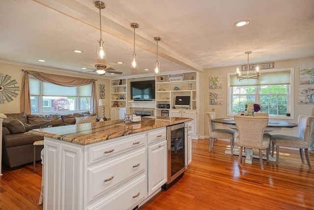 kitchen with beverage cooler, open floor plan, white cabinetry, and light wood-style flooring