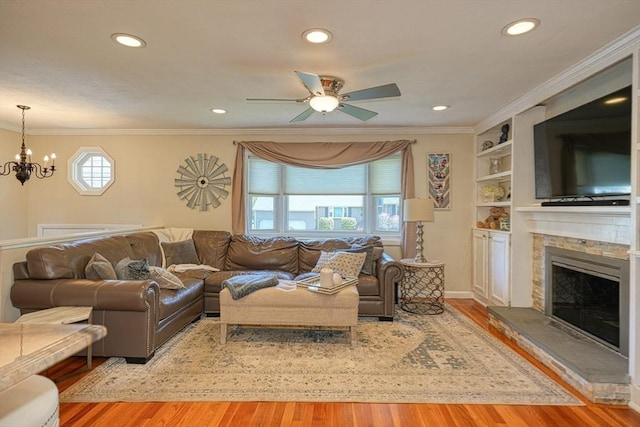 living room with crown molding, ceiling fan with notable chandelier, recessed lighting, and wood finished floors