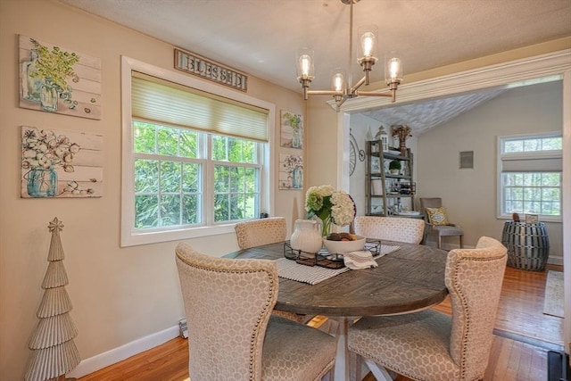 dining area with an inviting chandelier, baseboards, wood finished floors, and vaulted ceiling