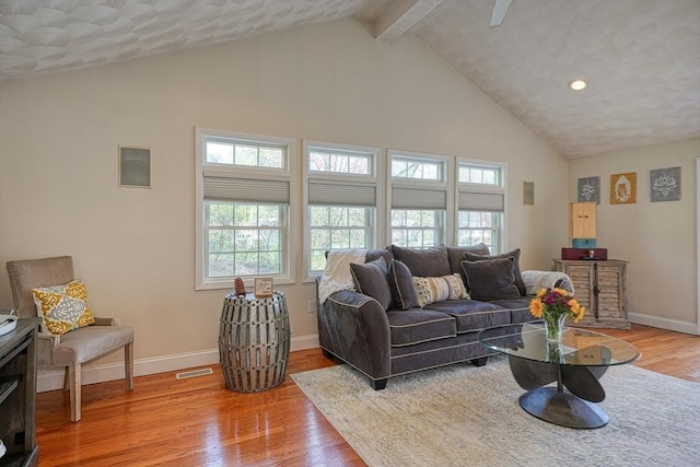 living area featuring high vaulted ceiling, baseboards, and light wood-style floors