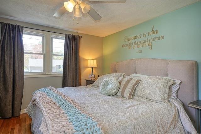 bedroom featuring baseboards, a textured ceiling, ceiling fan, and wood finished floors