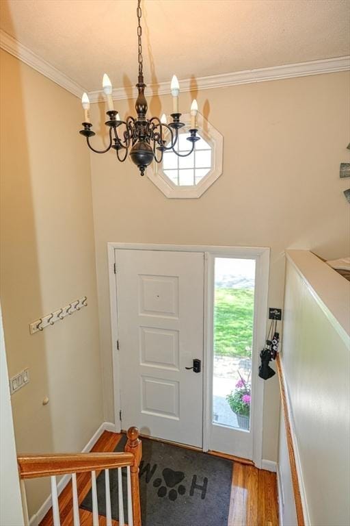 foyer entrance with ornamental molding, light wood-style flooring, and a chandelier