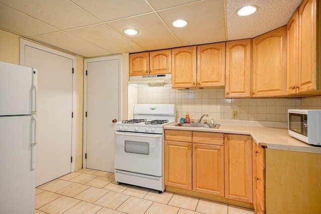 kitchen featuring a sink, white appliances, light countertops, decorative backsplash, and under cabinet range hood