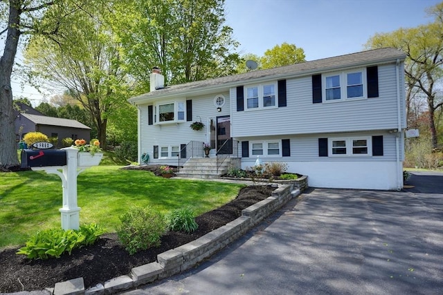 bi-level home with a chimney and a front lawn