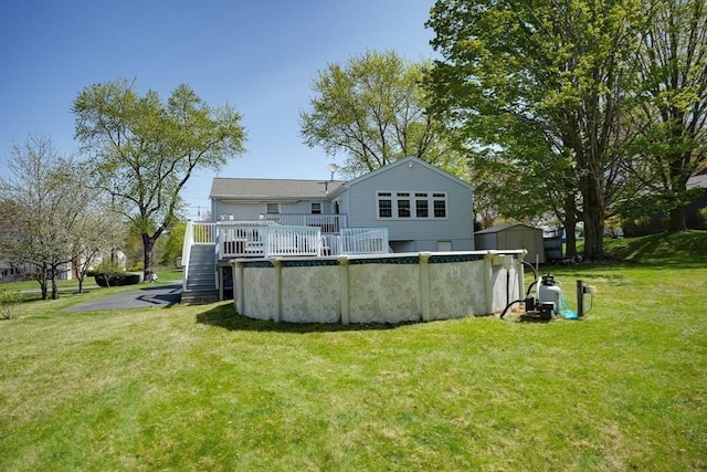 back of house with a wooden deck, an outdoor pool, a yard, a storage unit, and an outbuilding