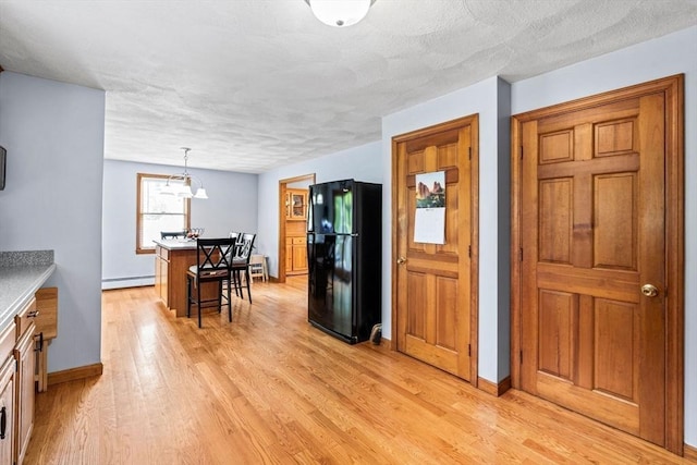 24 Floyd Ave, Tewksbury, MA 01876 - kitchen featuring freestanding refrigerator, light wood-style flooring, baseboards, a breakfast bar, and a textured ceiling