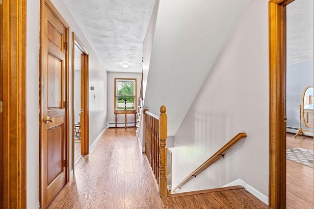 24 Floyd Ave, Tewksbury, MA 01876 - corridor featuring an upstairs landing, a baseboard heating unit, wood finished floors, and baseboards