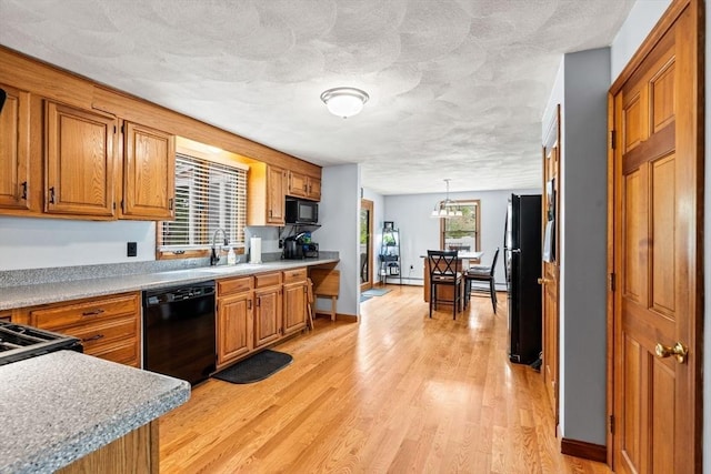 24 Floyd Ave, Tewksbury, MA 01876 - kitchen featuring black appliances, brown cabinetry, light wood finished floors, and a textured ceiling