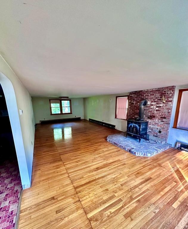 7 Lake Shore Dr, Georgetown, MA 01833 - unfurnished living room with a wood stove, light wood-style floors, and arched walkways