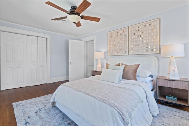 bedroom with ceiling fan, visible vents, wood finished floors, baseboards, and a closet