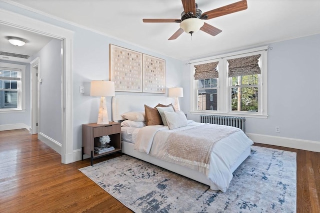 bedroom with baseboards, wood finished floors, and radiator