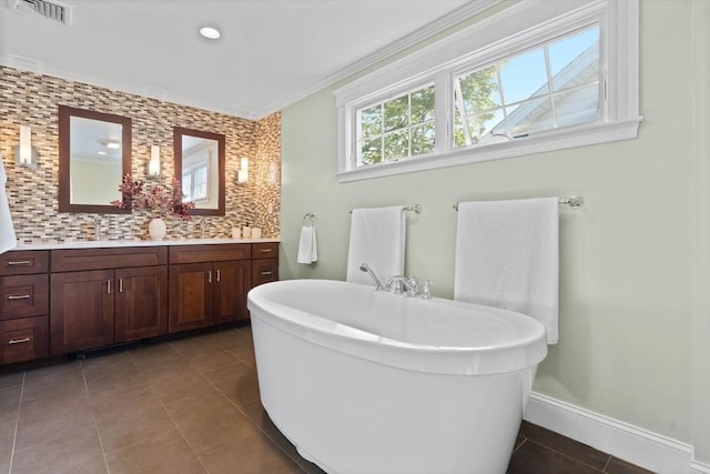 bathroom with a freestanding bath, a sink, tile patterned flooring, tasteful backsplash, and visible vents