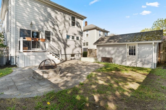 rear view of property featuring an outdoor structure, a patio area, and an outdoor fire pit