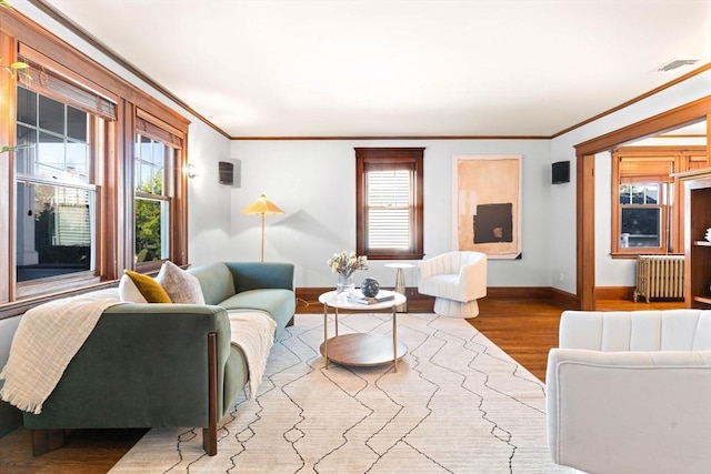 living room featuring crown molding, visible vents, radiator, wood finished floors, and baseboards
