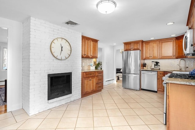 kitchen featuring visible vents, a sink, backsplash, appliances with stainless steel finishes, and a baseboard radiator