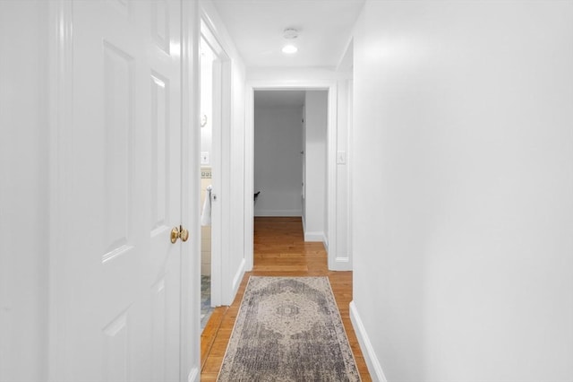 corridor with light wood-type flooring and baseboards