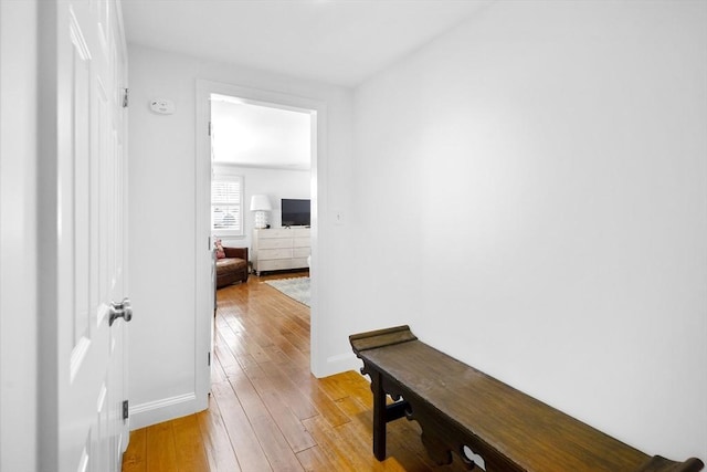 hall with light wood-type flooring and baseboards