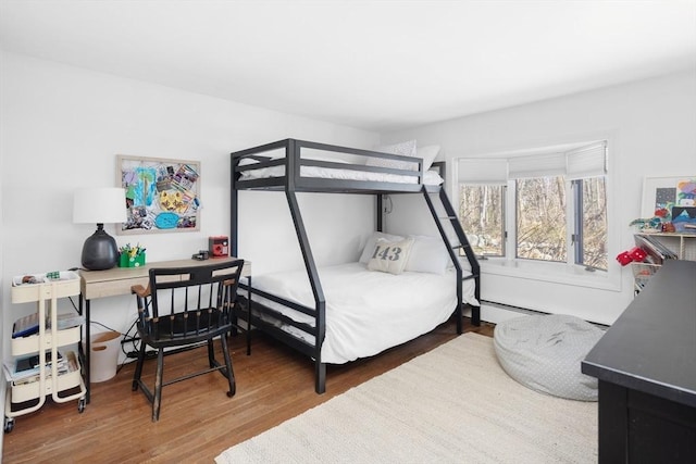 bedroom with wood finished floors and a baseboard radiator