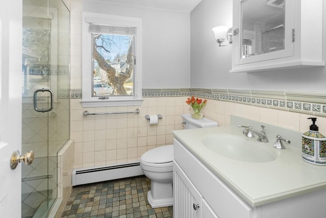 bathroom with a shower stall, toilet, vanity, tile walls, and a baseboard radiator