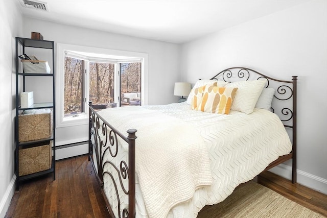 bedroom with dark wood finished floors, visible vents, a baseboard heating unit, and baseboards