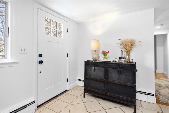 entryway featuring a baseboard heating unit, light tile patterned floors, baseboards, and baseboard heating