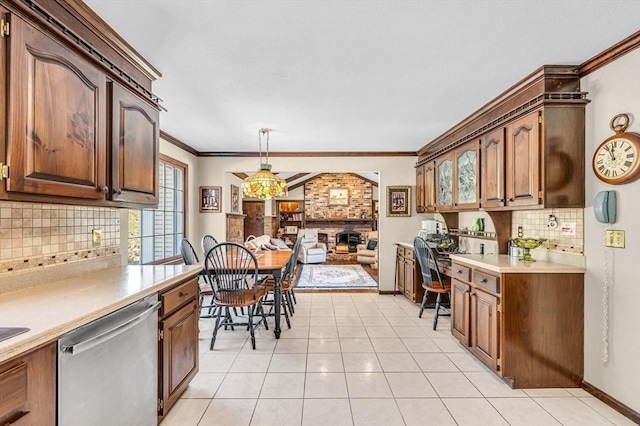 kitchen featuring pendant lighting, light tile patterned floors, crown molding, dishwasher, and tasteful backsplash