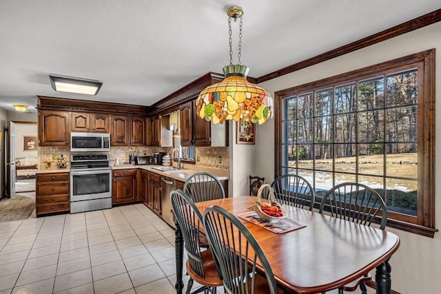 dining space with crown molding, sink, and light tile patterned floors