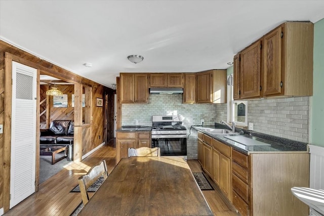 kitchen featuring stainless steel gas range oven, sink, and light wood-type flooring