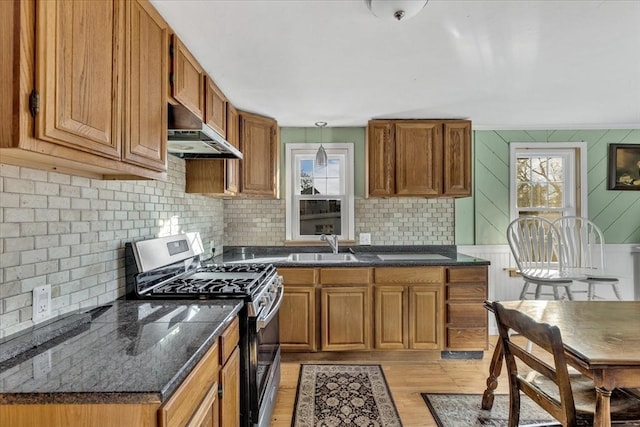 kitchen featuring sink, hanging light fixtures, stainless steel gas range oven, light hardwood / wood-style floors, and exhaust hood